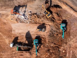 Aerial view road motor grader flatting dirt road surface, Motor grader road construction grader industrial machine construction site new road, Aerial view group excavator working on construction site.