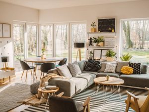 Wooden, round dining table in the corner of an open space living room interior with nordic furniture and decor